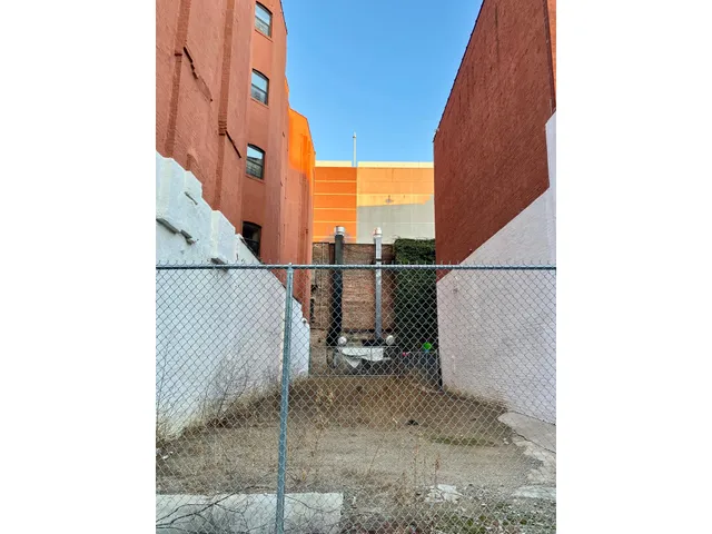 a picture of a room with a white wall and bed