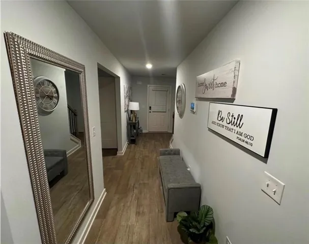 a view of a hallway to a bedroom with wooden floor and stairs