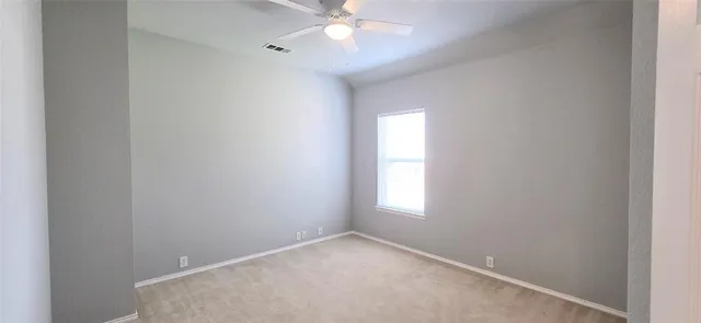 an empty room with a window and a chandelier fan