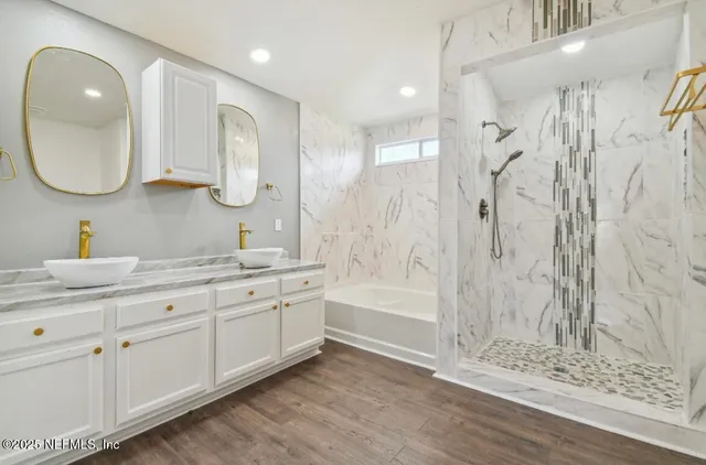 a bathroom with a double vanity sink mirror and bathtub