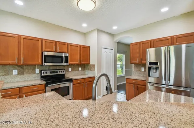 a kitchen with stainless steel appliances granite countertop a refrigerator a stove top oven a sink and dishwasher