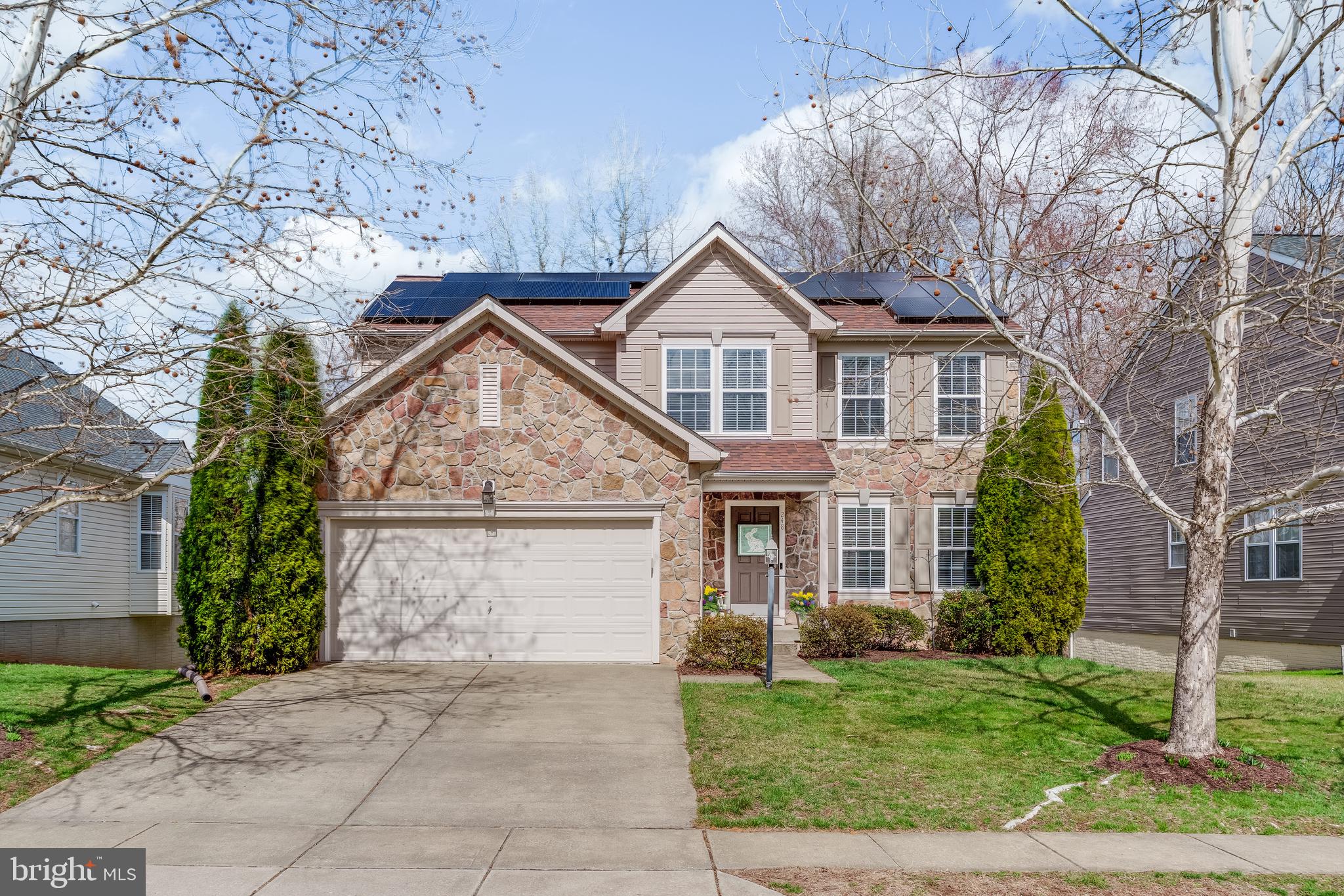 a view of a white house next to a yard with big trees