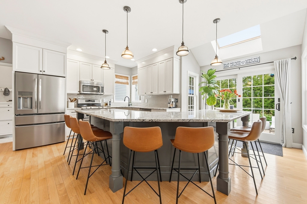 6 Hancock Road Franklin, MA 02038 - Photo 11 of 32 a kitchen with stainless steel appliances granite countertop a table chairs wooden floors a large window and a kitchen island