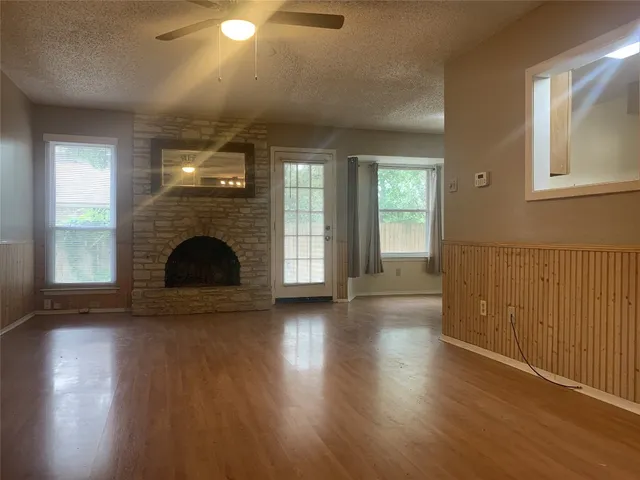an empty room with wooden floor fireplace and windows