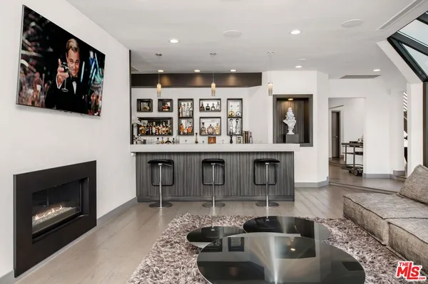a living room with stainless steel appliances furniture a fireplace and a flat screen tv