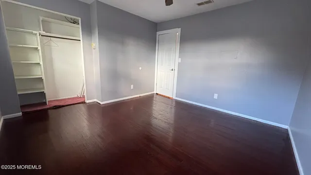 an empty room with wooden floor & windows