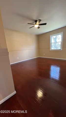 an empty room with wooden floor fan and windows
