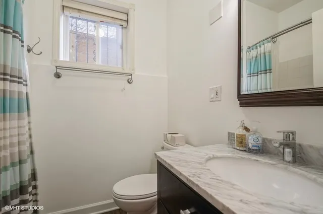a bathroom with a granite countertop toilet sink and mirror