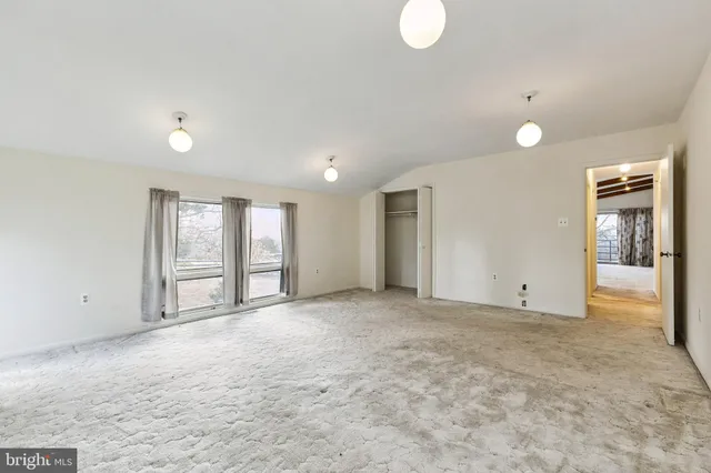 a view of an empty room with window and bathroom