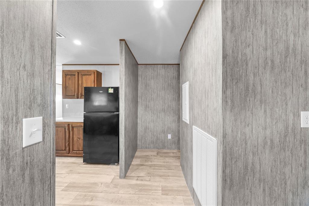 9160 Southwest 31st Avenue Road Ocala, FL 34476 - Photo 12 of 30 a view of a refrigerator in kitchen and an empty room with wooden floor