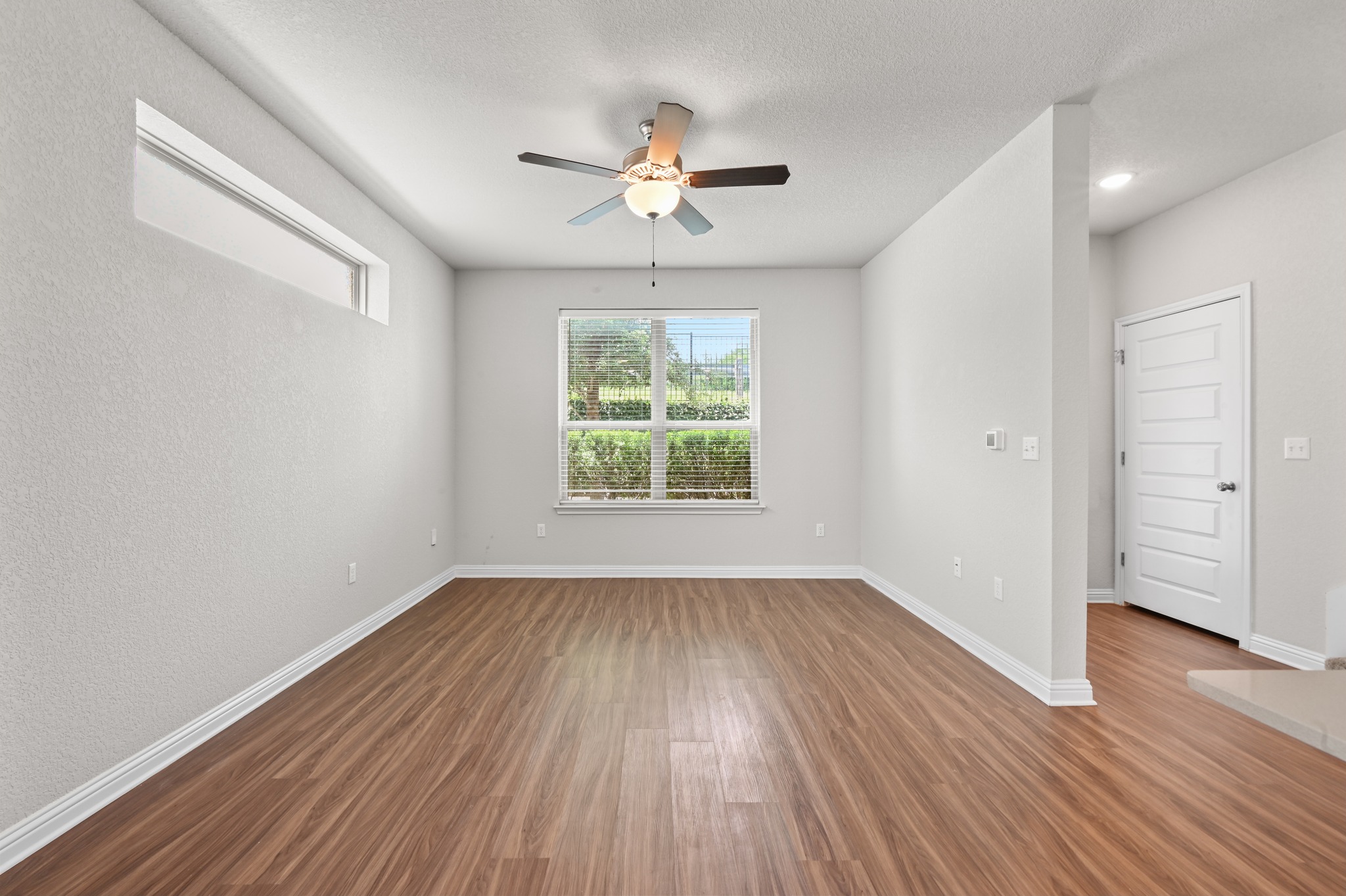 8201 Frida Bend Austin, TX 78744 - Photo 11 of 29 A versatile living area with a ceiling fan offers comfort and style on rich wood flooring.