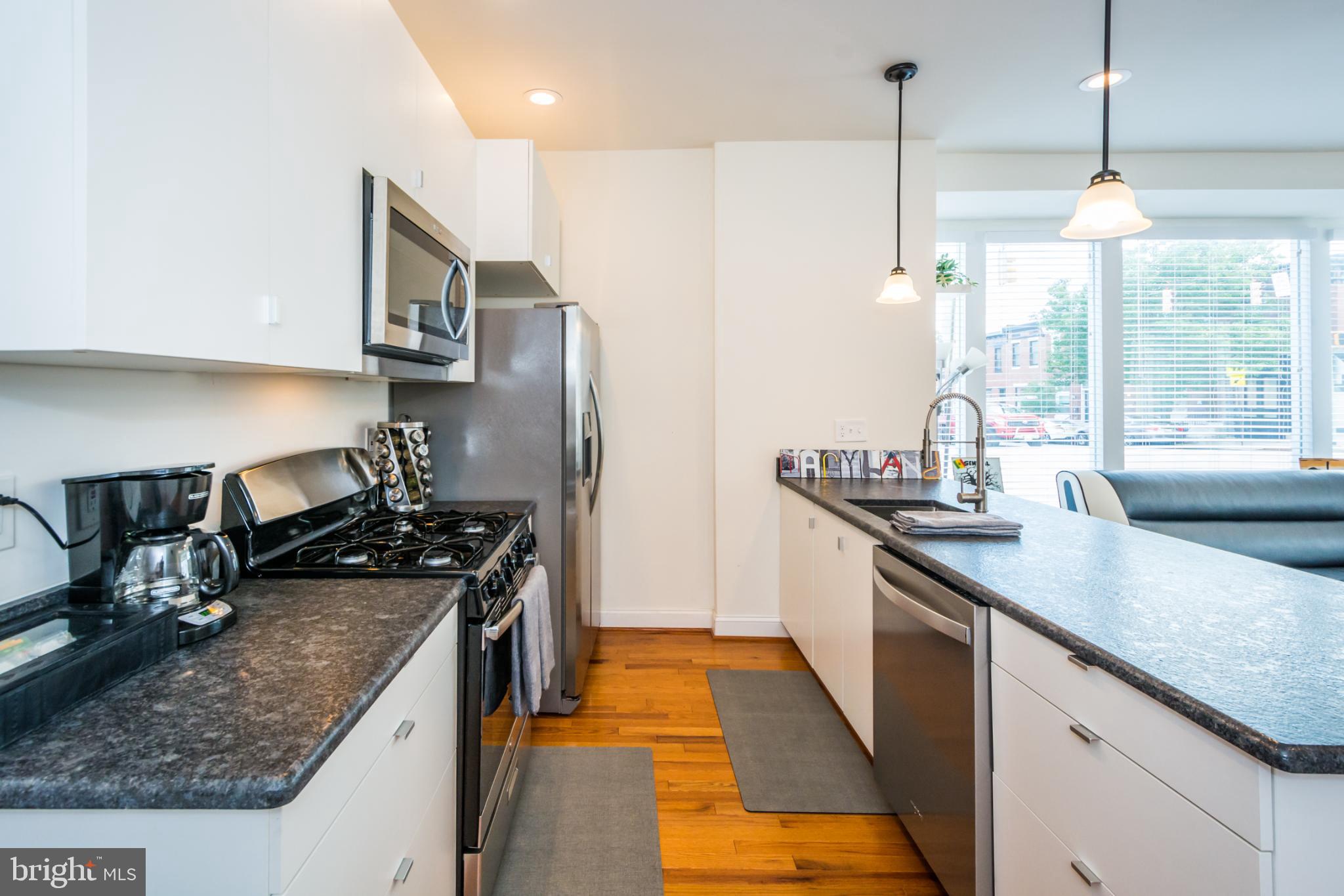 600 South Linwood Avenue, Unit A Baltimore, MD 21224 - Photo 7 of 33 a kitchen with stainless steel appliances granite countertop a sink a stove and a wooden floors