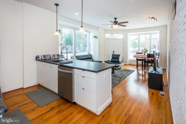 a kitchen with stainless steel appliances granite countertop wooden floors and view of living room