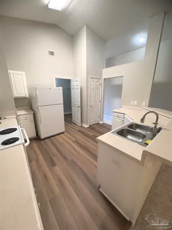 a open kitchen with stainless steel appliances a white stove top oven a sink and a refrigerator