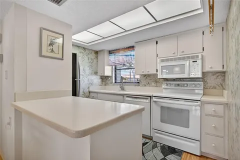 a kitchen with stainless steel appliances white cabinets and wooden floor