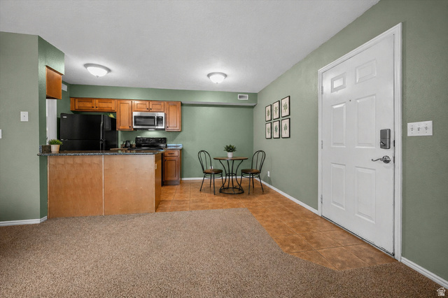 2095 South Main Street, Unit 13 Bountiful, UT 84010 - Photo 6 of 45 Kitchen featuring wood finish cabinetry, black appliances, light tile patterned floors, and light carpet
