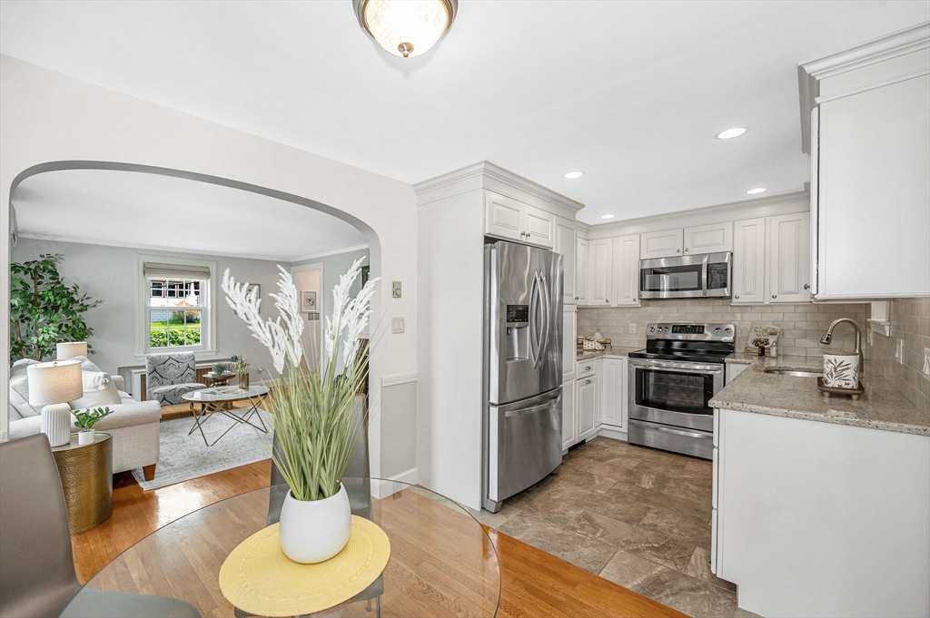 15 Eustis Avenue Wakefield, MA 01880 - Photo 9 of 42 a kitchen with stainless steel appliances kitchen island granite countertop a refrigerator a stove a oven with a dining table and chairs