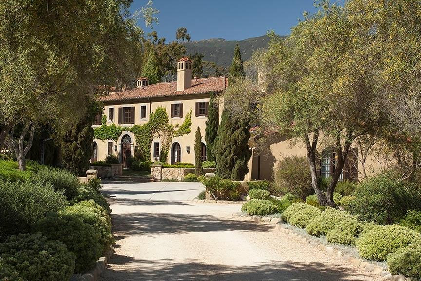 a view of a big house with large trees and plants