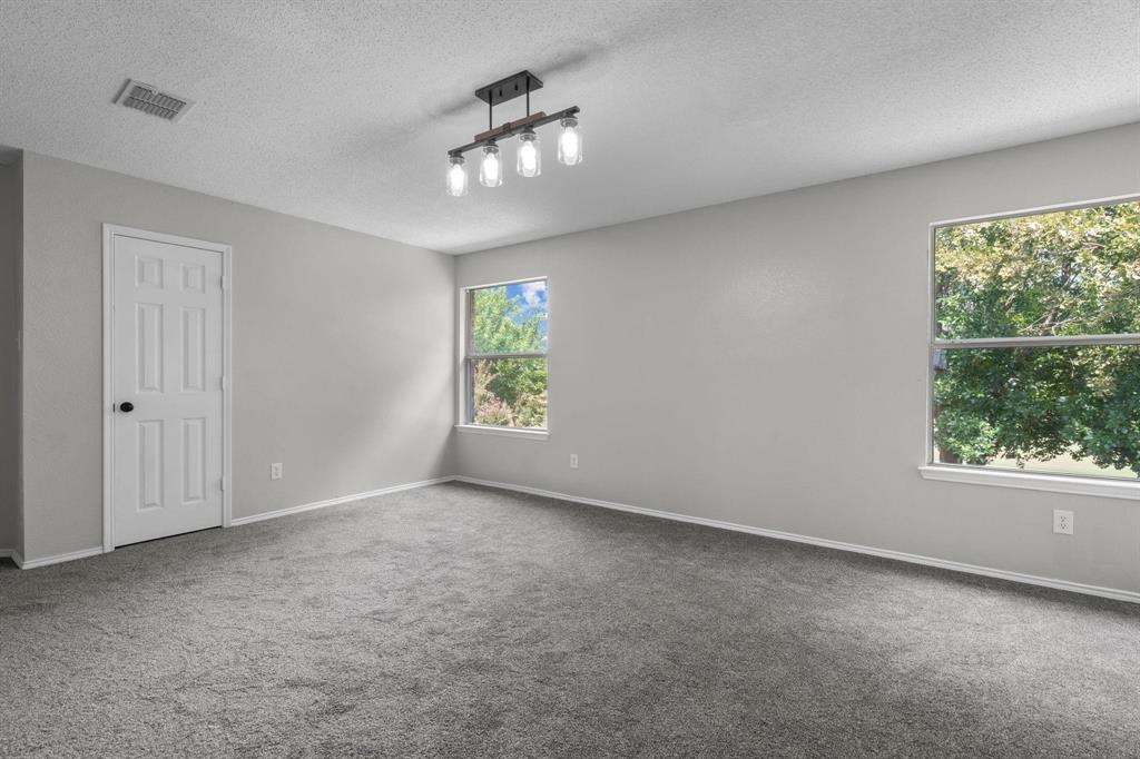 10618 Newcastleton Lane Rowlett, TX 75089 - Photo 11 of 13 an empty room with windows and chandelier fan