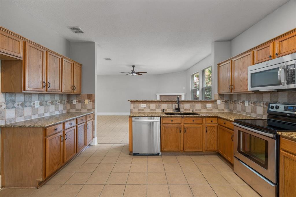 10618 Newcastleton Lane Rowlett, TX 75089 - Photo 6 of 13 a kitchen with stainless steel appliances granite countertop a stove top oven a sink dishwasher and a microwave oven on the blue kitchen countertops