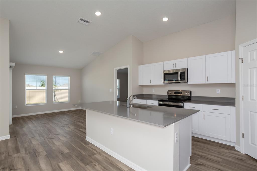1338 Palmeroy Road Haines City, FL 33844 - Photo 9 of 32 a kitchen with stainless steel appliances a stove a sink a refrigerator white cabinets and wooden floor