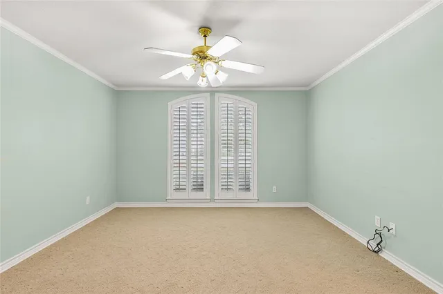 an empty room with chandelier fan and windows