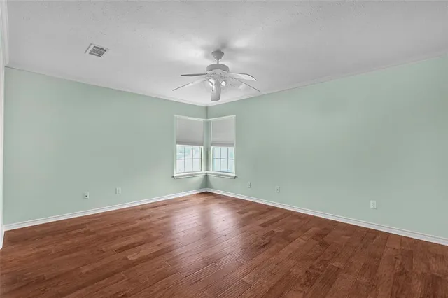 a view of an empty room with window and wooden floor
