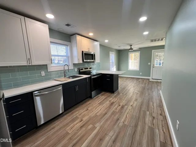 a kitchen with a sink a stove cabinets and wooden floor