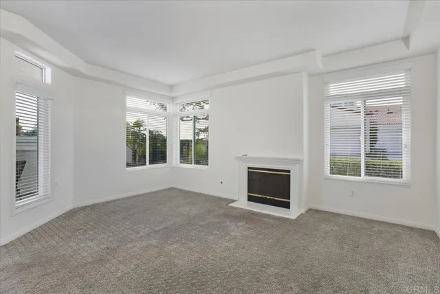 an empty room with windows and fireplace