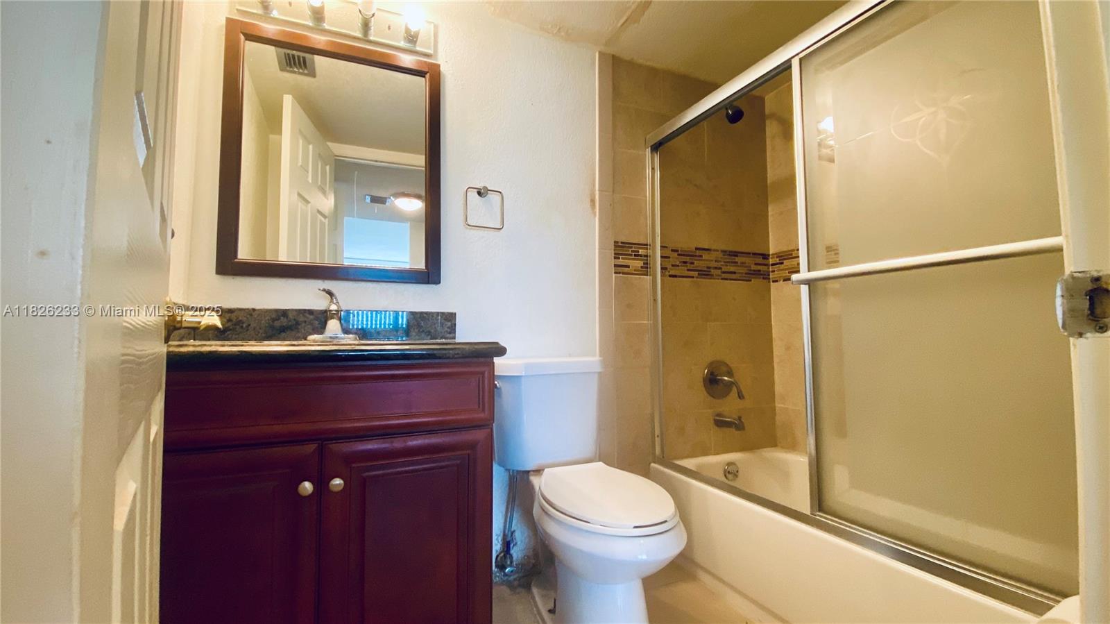 2025 Northeast 164th Street, Unit 901 North Miami Beach, FL 33162 - Photo 6 of 12 a bathroom with a granite countertop toilet sink and shower
