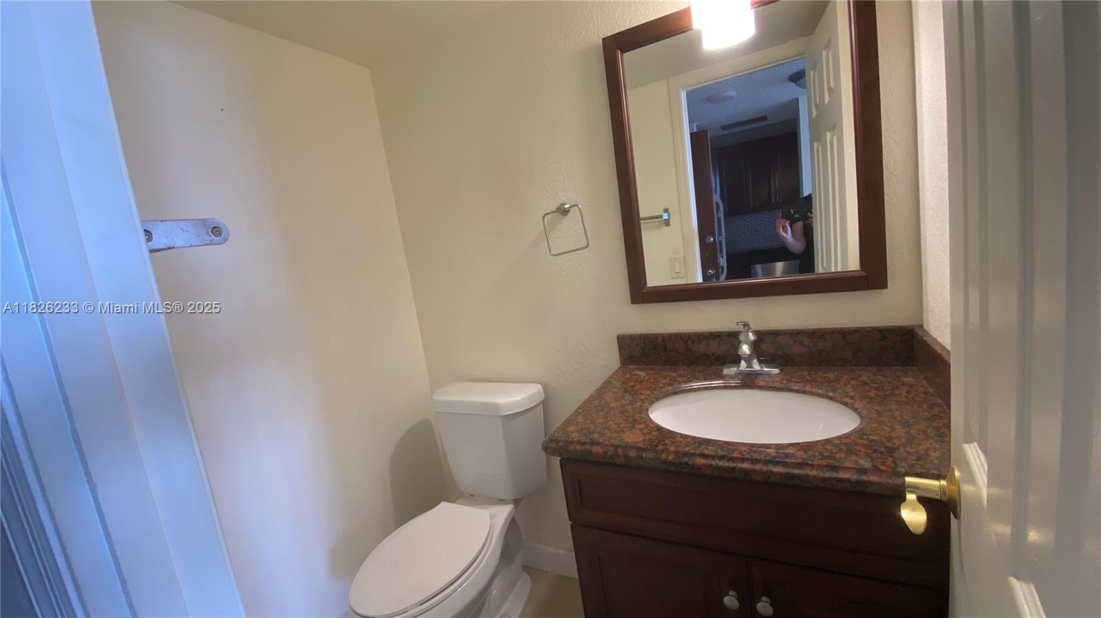 2025 Northeast 164th Street, Unit 901 North Miami Beach, FL 33162 - Photo 7 of 12 a bathroom with a granite countertop toilet sink and mirror