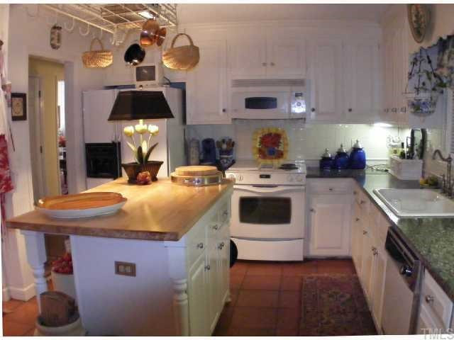 128 Bayleaf Drive Raleigh, NC 27615 - Photo 4 of 12 Kitchen has granite counters, butcher block island, pot rack, terra cotta tile floors, updated range and microwave. Kitchen
