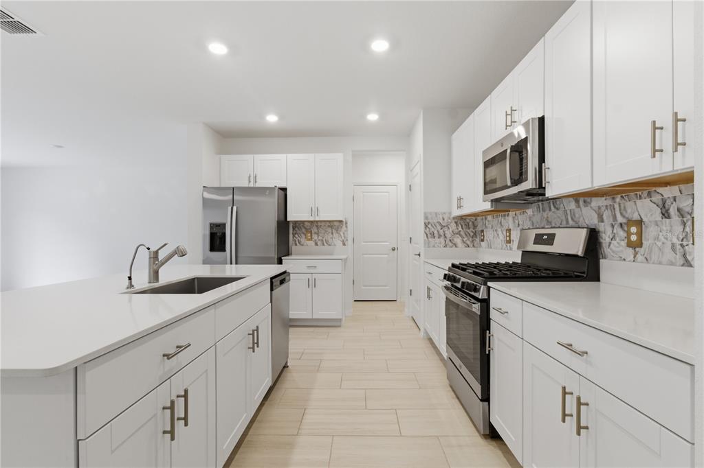2455 Lanier Road Zephyrhills, FL 33541 - Photo 12 of 39 a kitchen with stainless steel appliances granite countertop a sink and dishwasher a stove top oven with white cabinets