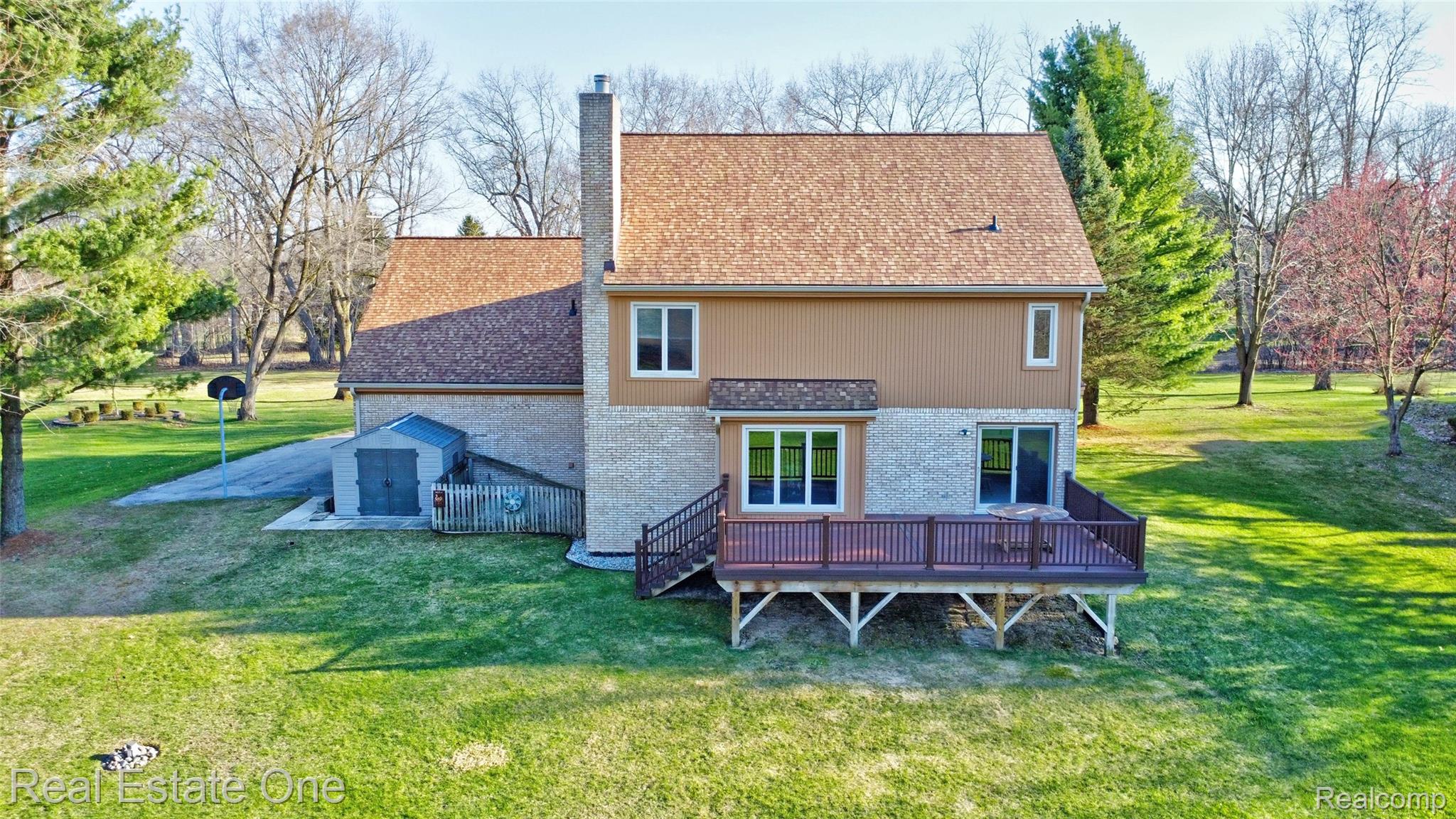 6400 Oakhill Road Ortonville, MI 48462 - Photo 56 of 82 Back of house featuring a lawn, brick siding, a deck, and a chimney