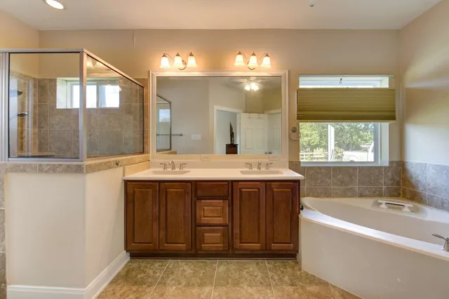 a spacious bathroom with a tub sink and mirror