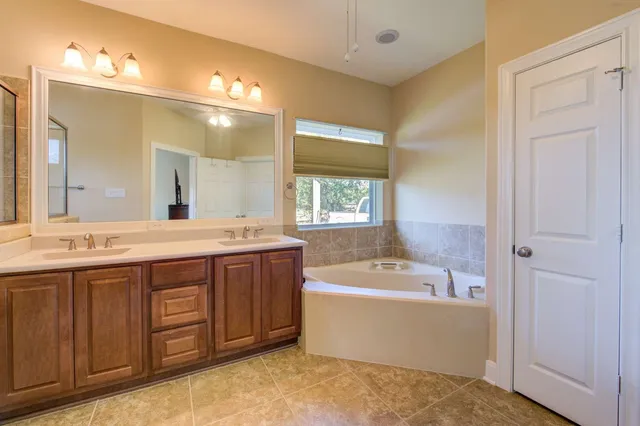 a spacious bathroom with a tub sink shower and mirror