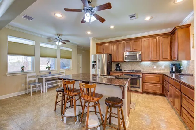 a kitchen with stainless steel appliances granite countertop table chairs sink and cabinets