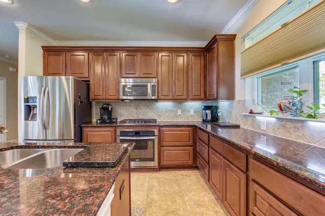 a kitchen with stainless steel appliances granite countertop a sink stove and refrigerator