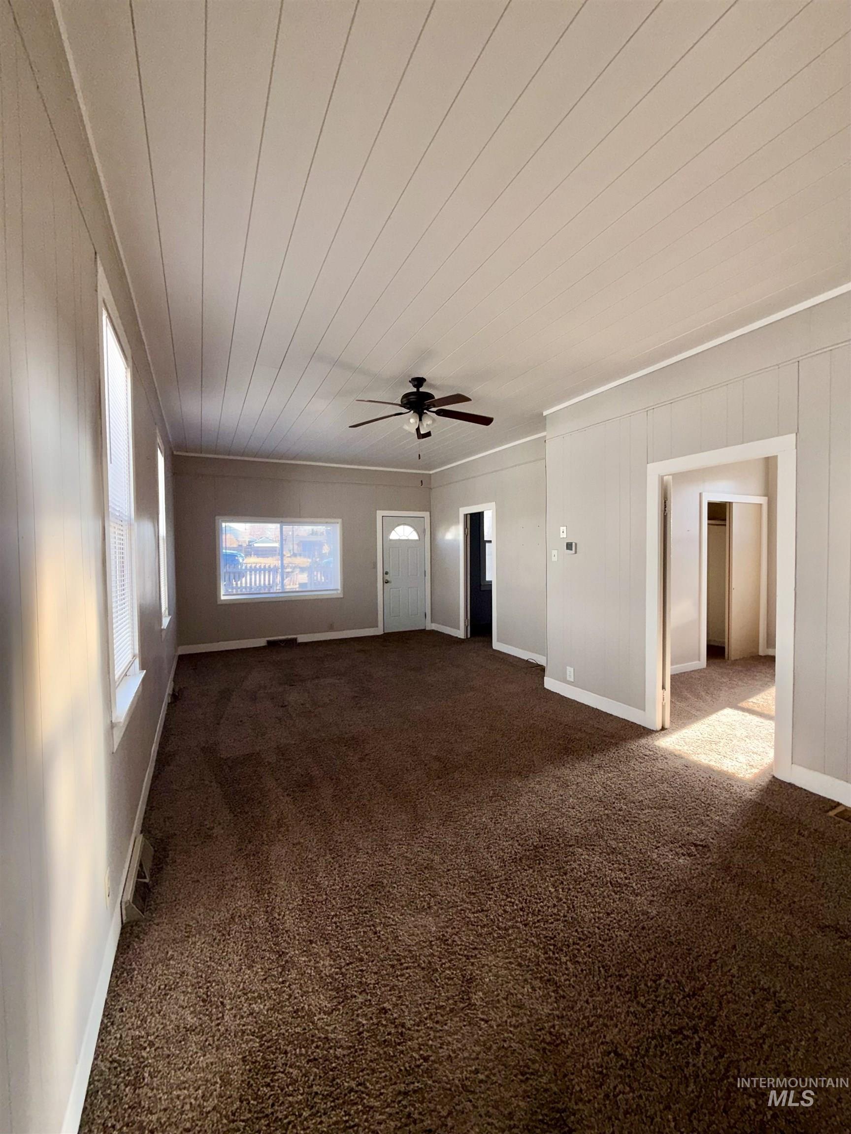 478 2nd Street West Hansen, ID 83334 - Photo 4 of 15 Unfurnished living room featuring a ceiling fan, dark carpet, wooden ceiling, and crown molding