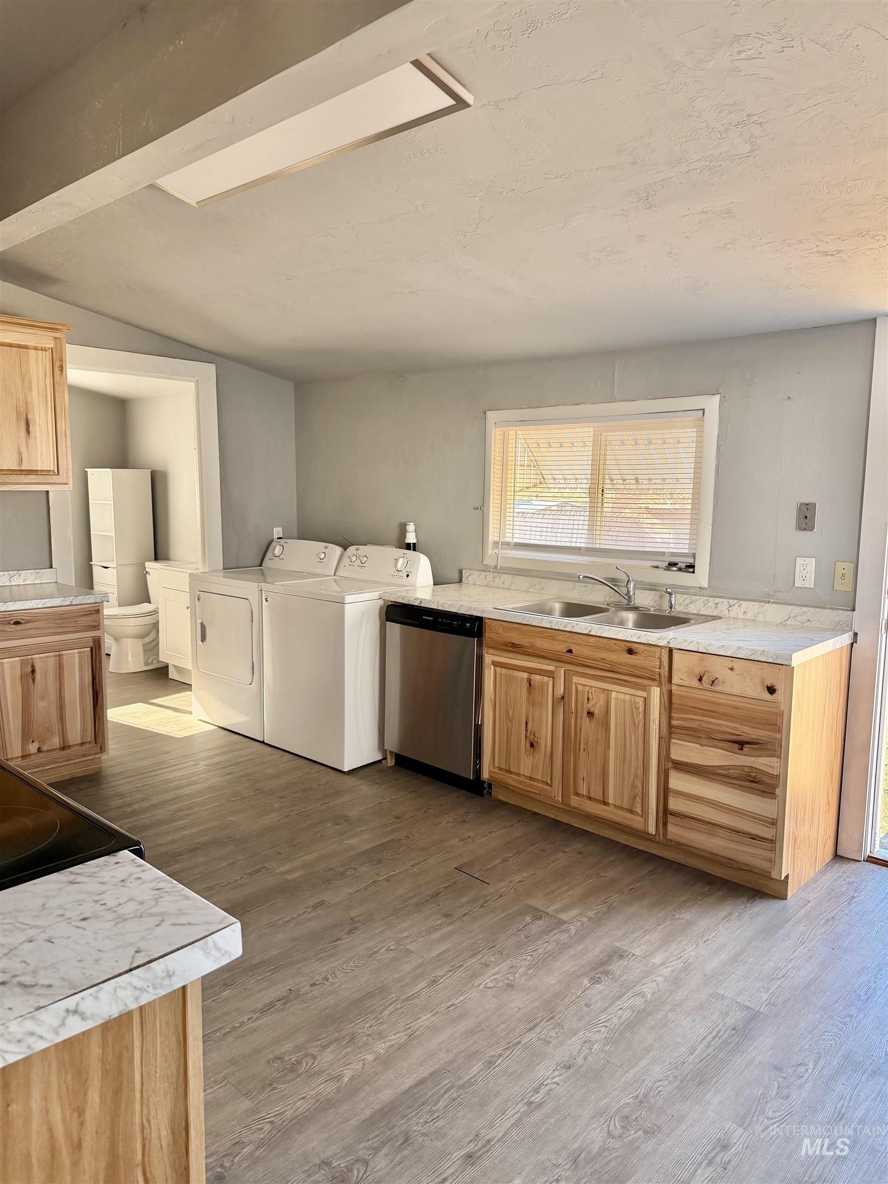 478 2nd Street West Hansen, ID 83334 - Photo 6 of 15 Kitchen featuring light countertops, light wood finish cabinetry, dishwasher, light wood-type flooring, and lofted ceiling