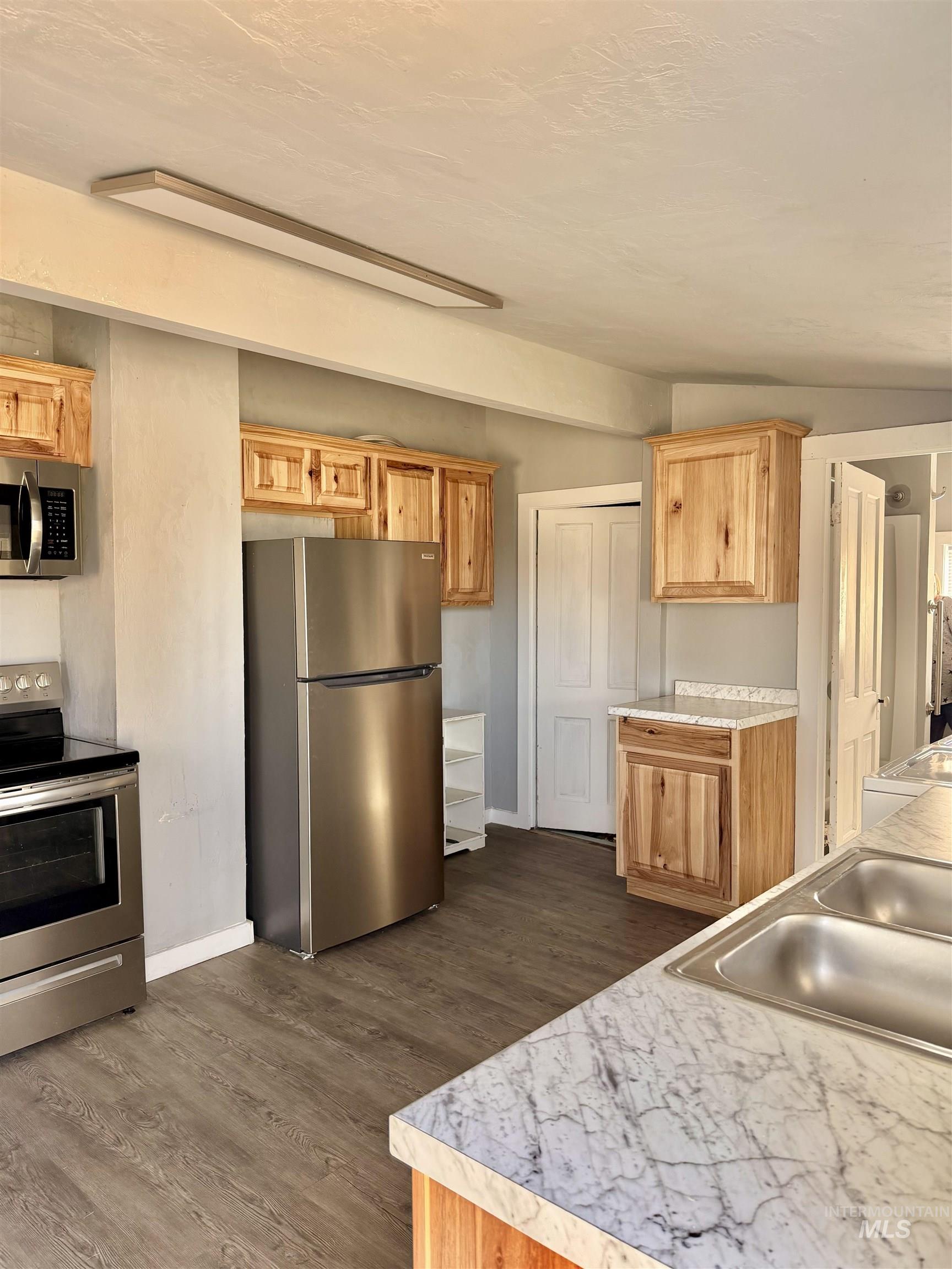 478 2nd Street West Hansen, ID 83334 - Photo 8 of 15 Kitchen with stainless steel appliances, light countertops, dark wood-style flooring, vaulted ceiling, and light wood finish cabinetry