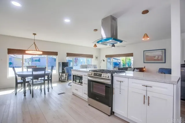 a kitchen with a stove a chandelier and chairs
