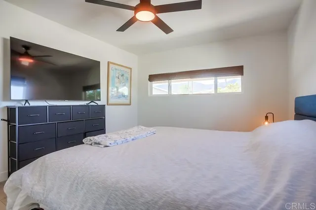 a bedroom with a bed and a flat tv screen on dresser
