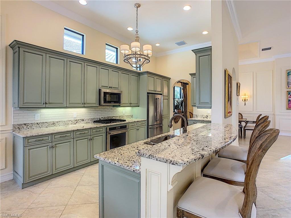 14693 Reserve Lane Naples, FL 34109 - Photo 12 of 34 a kitchen with kitchen island granite countertop a sink stainless steel appliances and chandelier