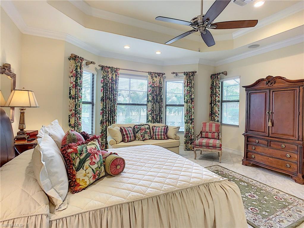 14693 Reserve Lane Naples, FL 34109 - Photo 19 of 34 a bedroom with a bed a dresser and a chandelier