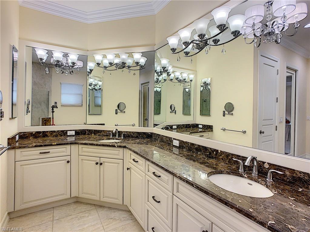 14693 Reserve Lane Naples, FL 34109 - Photo 21 of 34 a bathroom with a granite countertop sink a large mirror and a white wooden cabinets