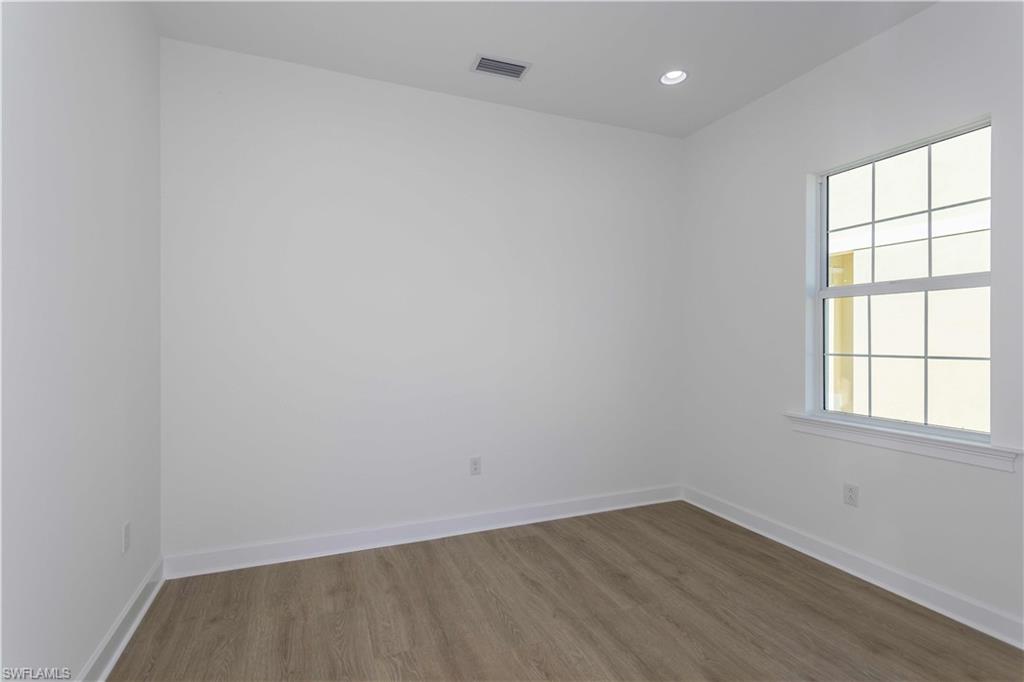9004 Calypso Court Naples, FL 34113 - Photo 13 of 44 an empty room with wooden floor and windows