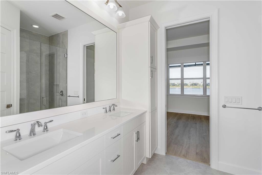 9004 Calypso Court Naples, FL 34113 - Photo 17 of 44 a spacious bathroom with double vanity and a mirror