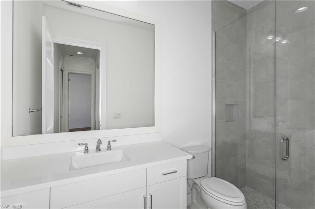 9004 Calypso Court Naples, FL 34113 - Photo 20 of 44 a bathroom with a toilet sink vanity and mirror
