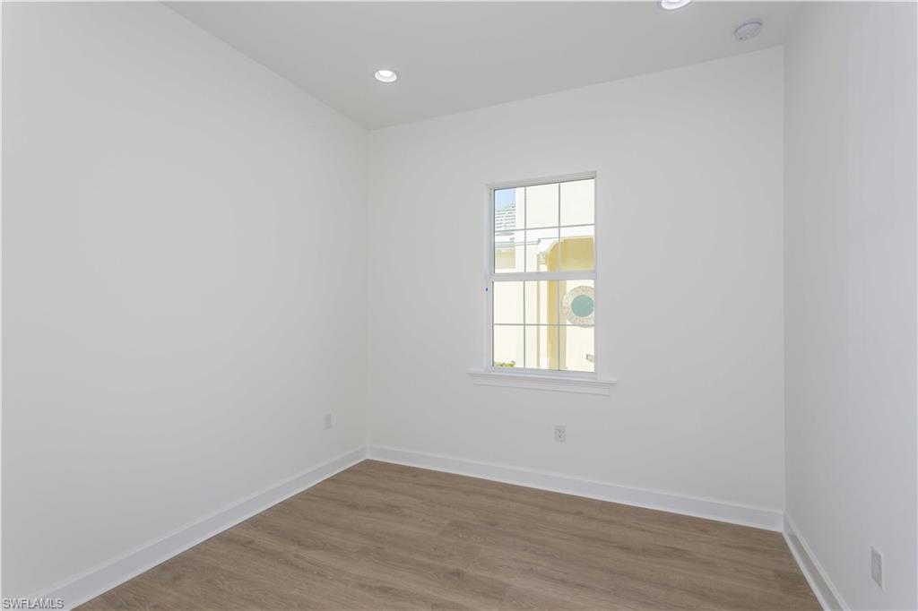 9004 Calypso Court Naples, FL 34113 - Photo 21 of 44 an empty room with wooden floor and windows